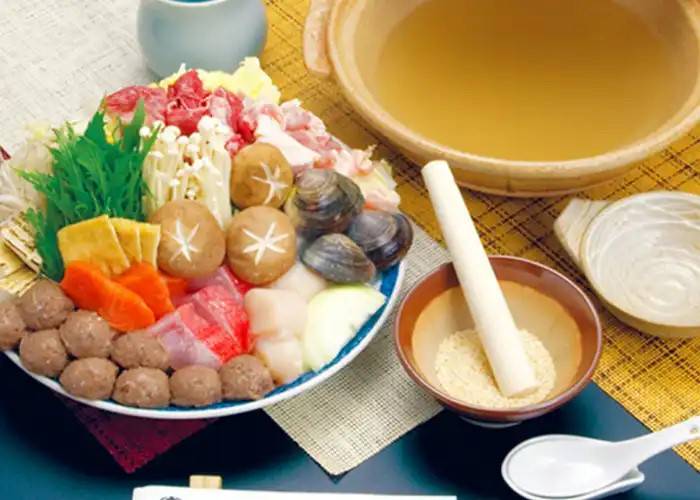 All the ingredients of chanko nabe, featuring broth, seasonal, and a bowl of meats and vegetables.